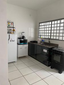 a kitchen with a black counter and a white refrigerator at mazzonetto ap 03 in Primavera do Leste