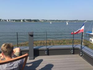 a man sitting on a deck looking at the water at Fjordhaus Schleiwind in Fahrdorf