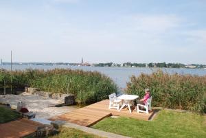 a woman sitting at a table on a wooden deck near the water at Fjordhaus Schleiwind in Fahrdorf +27 photos