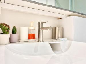 a white sink in a bathroom with plants at " L'Atelier Signature " Piscine - Terrasse - Wifi in Toulouse +19 photos
