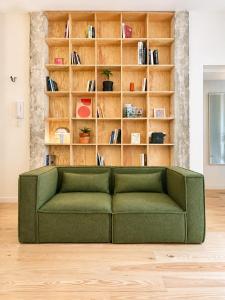 a green couch in a room with a book shelf at " L'Atelier Signature " Piscine - Terrasse - Wifi in Toulouse