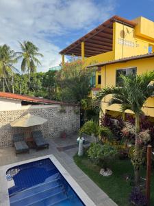 a villa with a swimming pool in front of a house at Flats Parada Obrigatoria in Maragogi