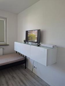 a living room with a tv on a white shelf at Pension Rückert in Kassel