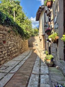 an alley in an old stone building with potted plants at Loft in Love in Spello