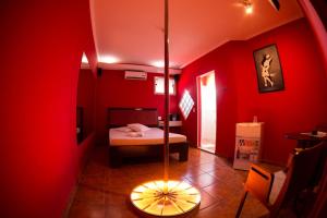 a red room with a bedroom with a bed and a table at La Passion Motel LTDA EPP in Jaú