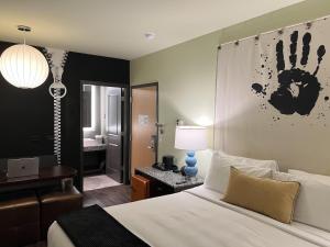 a bedroom with a bed and a desk with a hand on the wall at ACME Hotel Chicago, Outset Collection by Hilton in Chicago