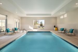 a swimming pool in a hotel room with blue chairs at TownePlace Suites by Marriott Hickory in Hickory