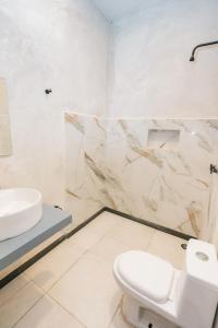 a white bathroom with a toilet and a sink at Casa Shalom Green in Bacalar