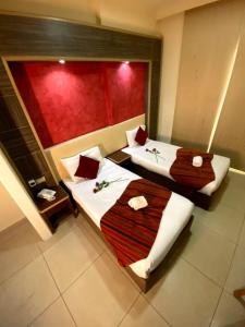two beds in a room with a red wall at Elysee Residence in Beirut