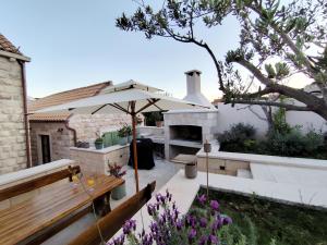 a patio with a bench and an umbrella at Villa Maranta in Slano