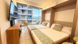 a hotel room with two beds and a television at Bello Horizonte, Aeropuerto, playa Dormida in Santa Marta