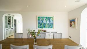 a dining room with a table and chairs and a painting at 5 The Cloisters - Waterville in Waterville