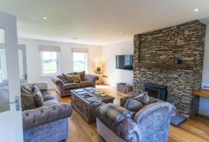 a living room with couches and a stone fireplace at 5 The Cloisters - Waterville in Waterville