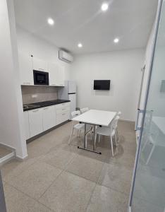a white kitchen with a white table and chairs at Piccola Chappy in Taranto