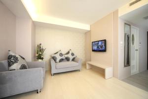 a living room with a couch and a tv on a wall at 宜都大飯店 Idol Hotel in Kaohsiung