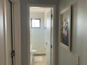a bathroom with a toilet and a painting on the wall at Lisboa Hospedaria 300 m da praia do forte in Cabo Frio