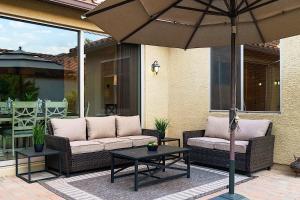 a patio with two couches and a table with an umbrella at Getaway at Power Ranch in Gilbert