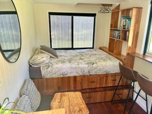 a small bedroom with a bed and a window at Bee Farm Off-Grid Tiny Home Stay in Tamaree