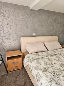 a bedroom with a bed and a nightstand next to it at Apartman Centar in Srbobran