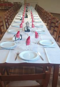 a long table with white plates and red napkins at Razem Lendina e Qete in Razëm