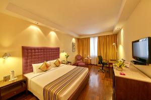 um quarto de hotel com uma cama e uma televisão de ecrã plano em Royal Orchid Central Bangalore, Manipal Centre, MG Road em Bangalore