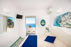 a white and blue bedroom with a view of the ocean at Casa Guadagno in Positano