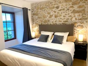 a bedroom with a large bed with a stone wall at Au Château de Villelongue B&B in Villelongue-dʼAude