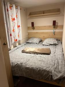 a bed with a blanket on it in a bedroom at La roulotte des écuries in Saint-Pierre-de-Chemillé