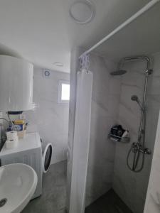 a white bathroom with a shower and a sink at Apartmani 'Cvit' in Karlobag
