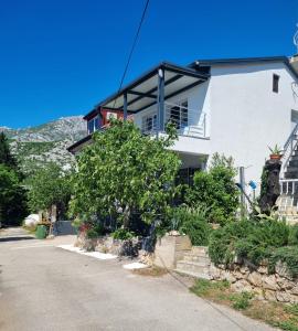 a white house with a tree in front of it at Apartmani 'Cvit' in Karlobag