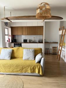 a living room with a yellow couch and a kitchen at Furadouro Cool & Cozy Flat in Furadouro