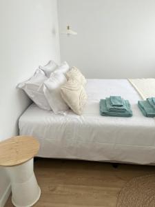 a white bed with white pillows and a table at Furadouro Cool & Cozy Flat in Furadouro