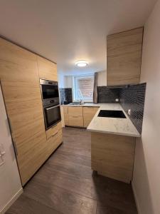 a small kitchen with wooden cabinets and a sink at Central leilighet i Kristiansand Vågsbygd in Kristiansand