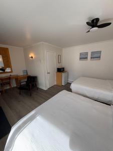 a hotel room with two beds and a desk at Le Délice Motel Restaurant in Mont-saint-pierre