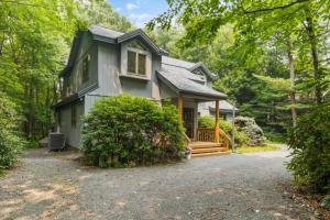 a house in the woods with a driveway at Split Rock Classic Chalet – Game Room & Family Friendly in Pocono Pines