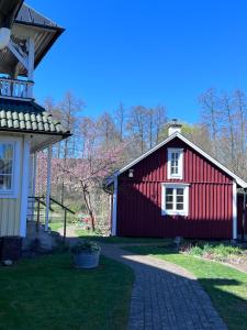 a red barn next to a house with a pathway at Isans stuga in Broby