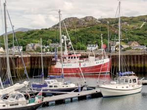 three boats are docked at a dock in the water at Seafield House in Lochinver