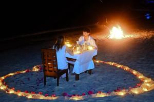a man and woman sitting at a table in the sand at Playa Encantada Beach Resort in El Nido