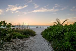a sandy beach with people on the water at 3B Beachfront Condo - Heated Pool & 18ft Balcony in Holmes Beach +38 photos