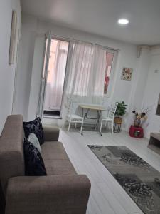 a living room with a couch and a table at Modern 1-Bedroom Apartment with AC, Free Parking & Self Check-in Bucharest-Militari in Dudu