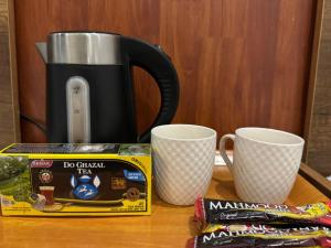 a coffee maker and two cups on a table at Koll Hotel in Erbil