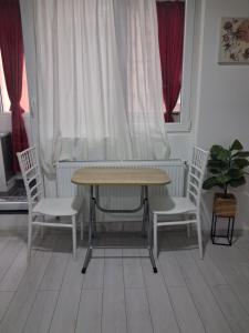 a table and two chairs and a table and two windows at Modern 1-Bedroom Apartment with AC, Free Parking & Self Check-in Bucharest-Militari in Dudu