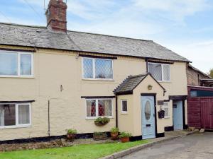 a yellow house with a blue door on a street at Rebecca's Cottage in Ashby Saint Ledgers