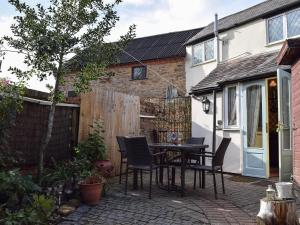 a patio with a table and chairs in a backyard at Rebecca's Cottage in Ashby Saint Ledgers