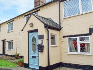 a house with a blue door and a window at Rebecca's Cottage in Ashby Saint Ledgers
