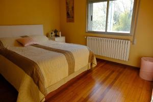a bedroom with a bed and a window and a wooden floor at Casa Rural Barxa in Monforte de Lemos