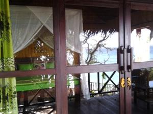 a view of the ocean through a glass door at Nini's Beach Bungalows in Bira