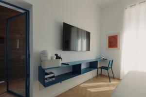 a bedroom with a desk with a tv on a wall at Andrew suites in Nettuno