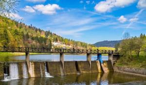 a bridge over a river with a waterfall at Resort ELSK Sekowski Krempna in Krempna