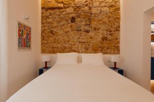 a bedroom with a white bed and a brick wall at Andrew suites in Nettuno